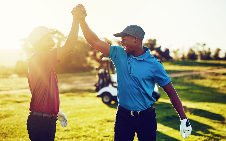 Two golfers high five on golf course.